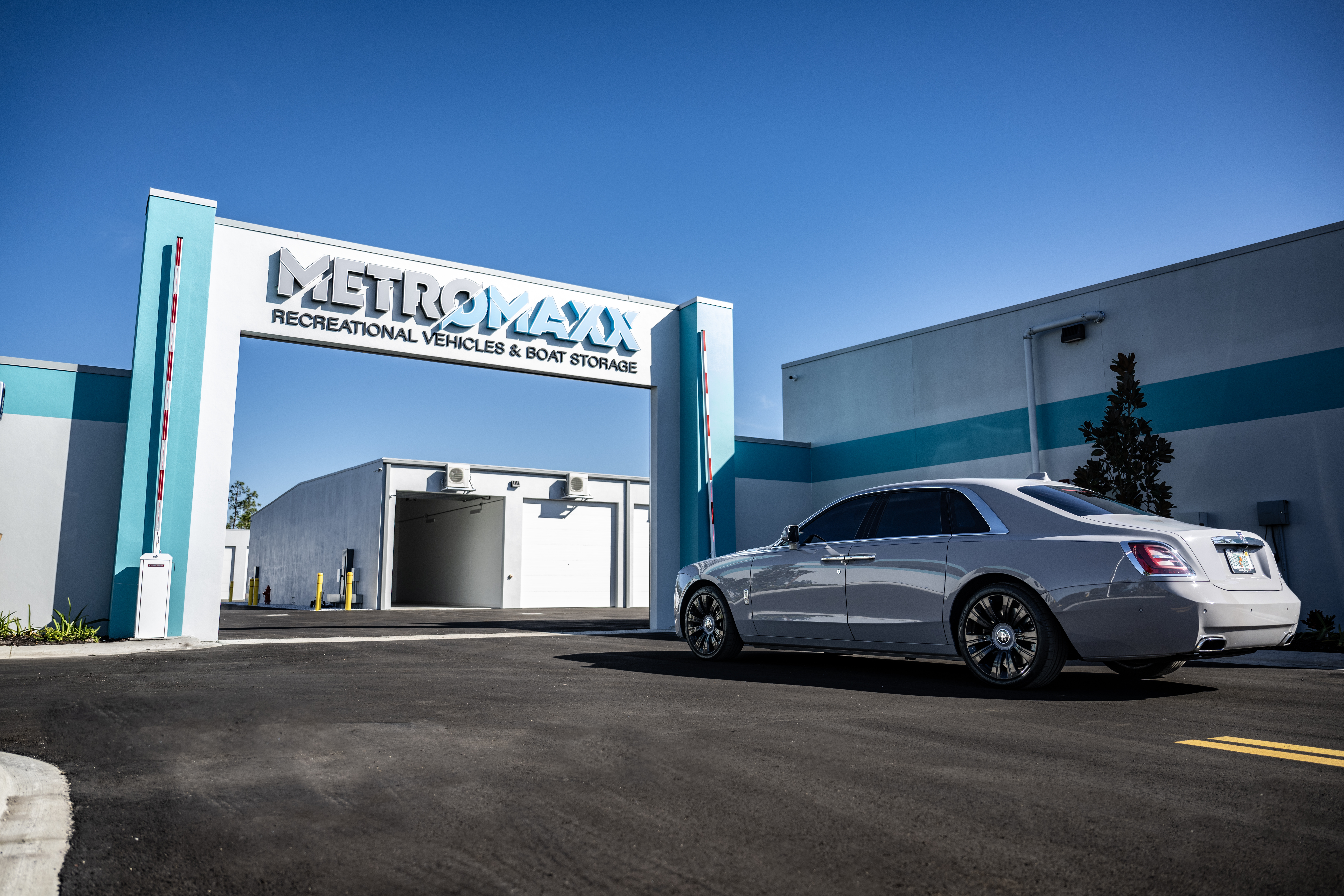 Luxury sedan entering the secure main entry gate at MetroMaxx Recreational Vehicles & Boat Storage in Fort Myers, Florida